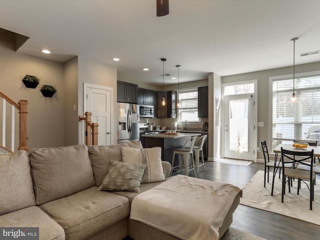 living area featuring dark wood-style flooring, recessed lighting, visible vents, stairway, and baseboards