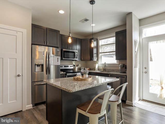 kitchen with light stone counters, dark brown cabinetry, visible vents, appliances with stainless steel finishes, and pendant lighting