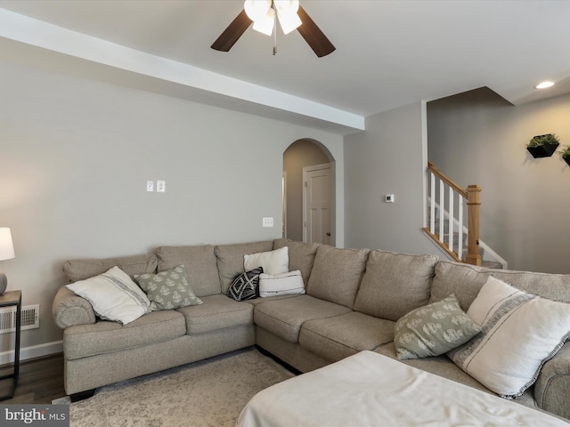 living room featuring arched walkways, wood finished floors, visible vents, a ceiling fan, and stairs