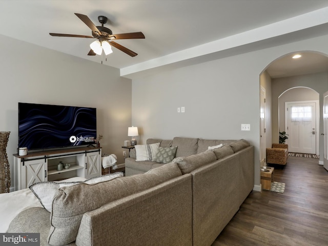 living room with arched walkways, dark wood finished floors, a ceiling fan, and baseboards