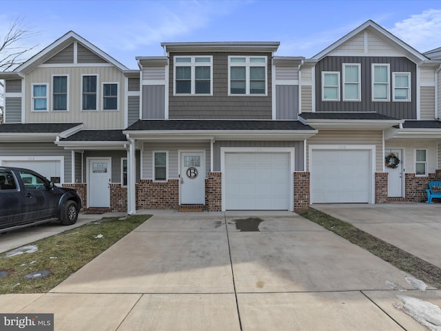 view of property with brick siding, driveway, and an attached garage