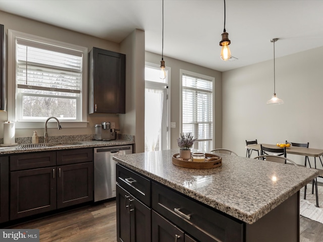 kitchen featuring dishwasher, a sink, a kitchen island, and decorative light fixtures