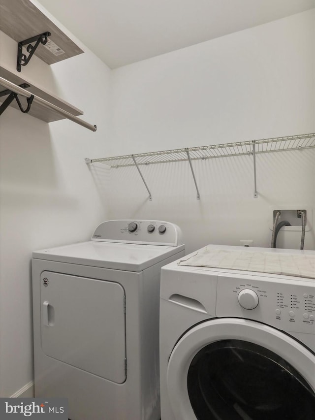 clothes washing area featuring laundry area, baseboards, and washing machine and clothes dryer