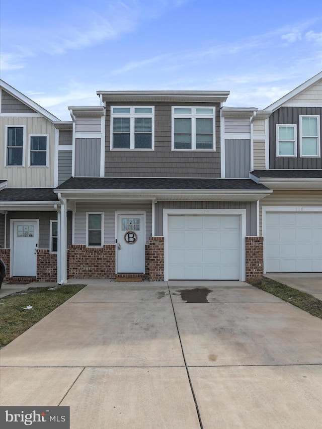 townhome / multi-family property with a garage, concrete driveway, and brick siding