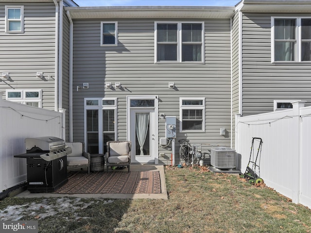 rear view of property with a fenced backyard, central AC unit, and a lawn