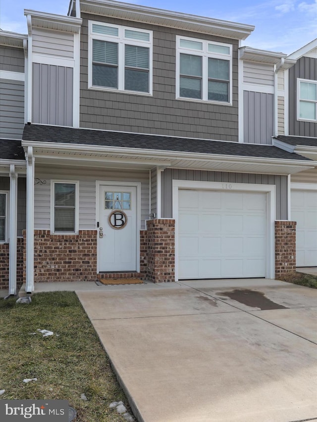 multi unit property with an attached garage, a shingled roof, concrete driveway, and brick siding