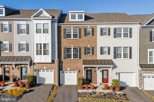 multi unit property with driveway, a shingled roof, a garage, and brick siding