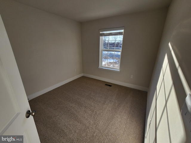 empty room with carpet floors, visible vents, and baseboards