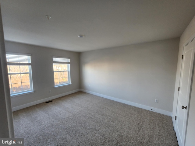 spare room featuring baseboards, visible vents, and light colored carpet