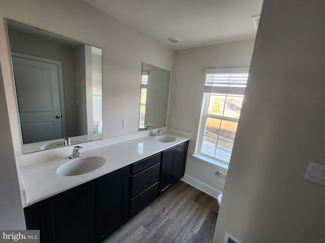 full bath with double vanity, wood finished floors, a sink, and toilet