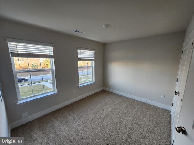 spare room featuring baseboards, visible vents, and carpet flooring