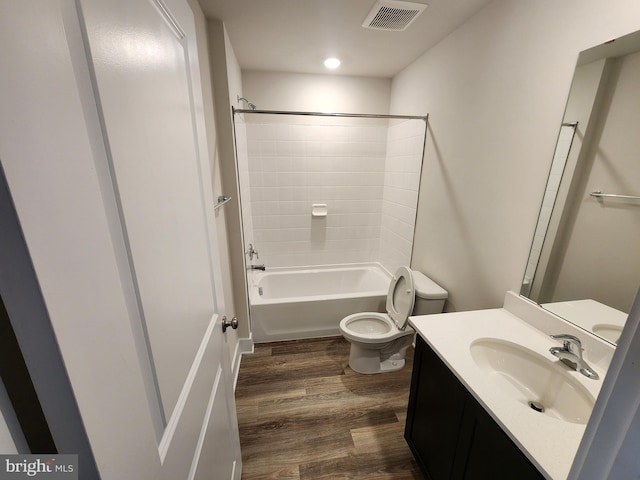 full bathroom with visible vents, toilet, wood finished floors,  shower combination, and vanity