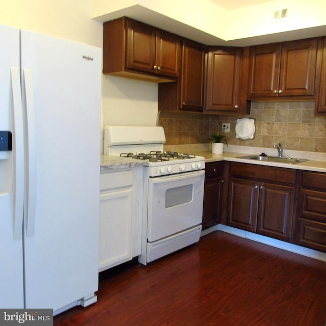 kitchen featuring tasteful backsplash, visible vents, dark wood-type flooring, a sink, and white appliances