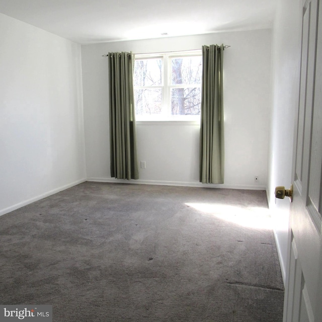 carpeted spare room featuring baseboards