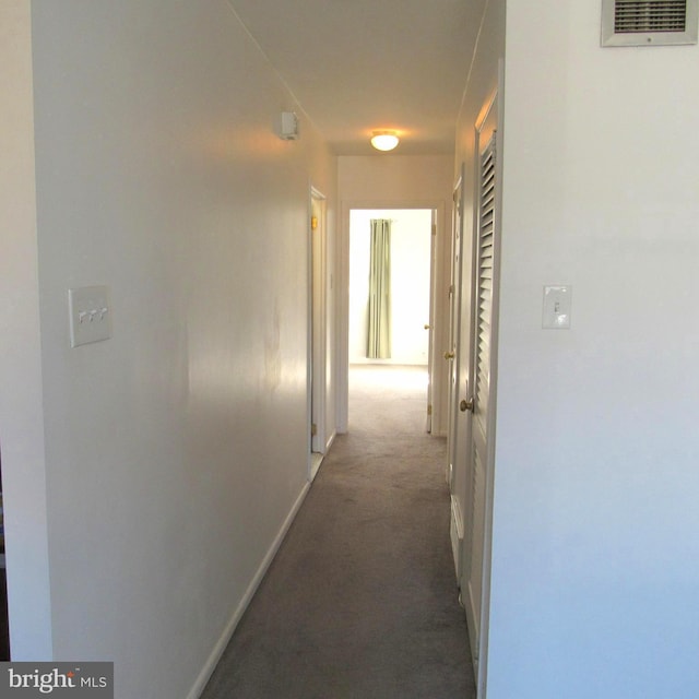 hall featuring baseboards, visible vents, and carpet flooring