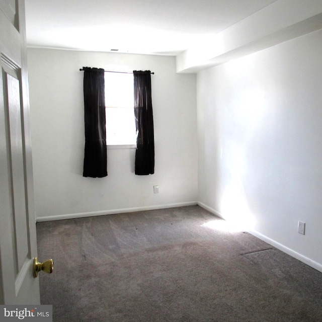 spare room with dark carpet and baseboards