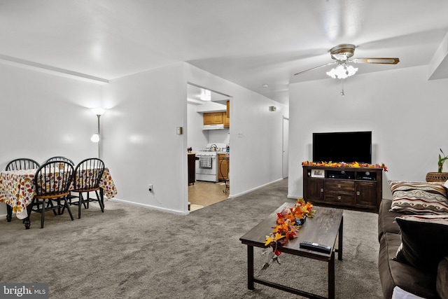 carpeted living area featuring ceiling fan and baseboards