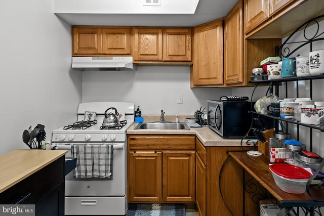 kitchen featuring stainless steel microwave, light countertops, white gas stove, under cabinet range hood, and a sink