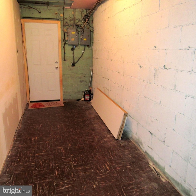 hall with concrete block wall and tile patterned floors