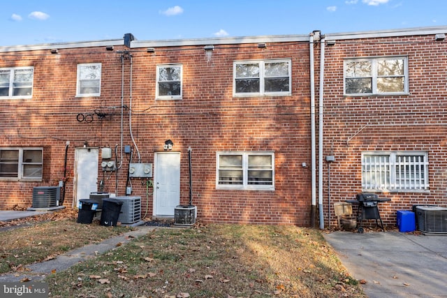 back of house with central AC and brick siding