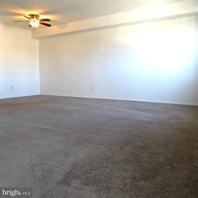 spare room featuring dark colored carpet and ceiling fan