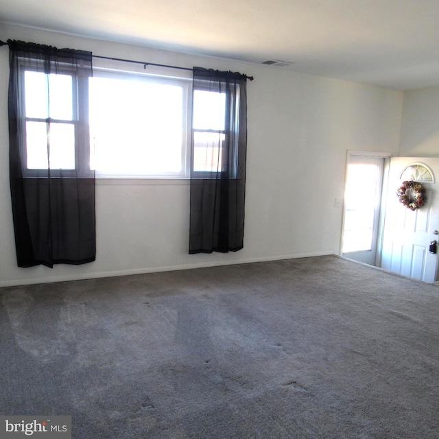 carpeted empty room featuring visible vents