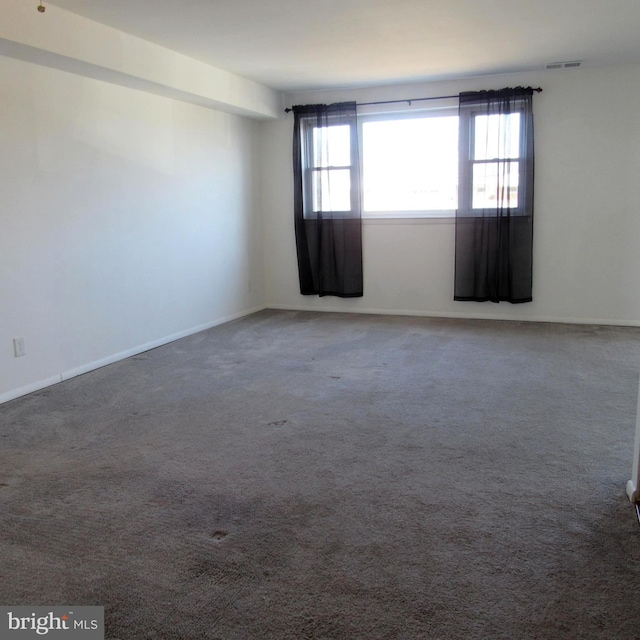 unfurnished room featuring carpet, visible vents, and baseboards