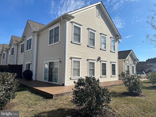 rear view of house featuring a deck and a lawn