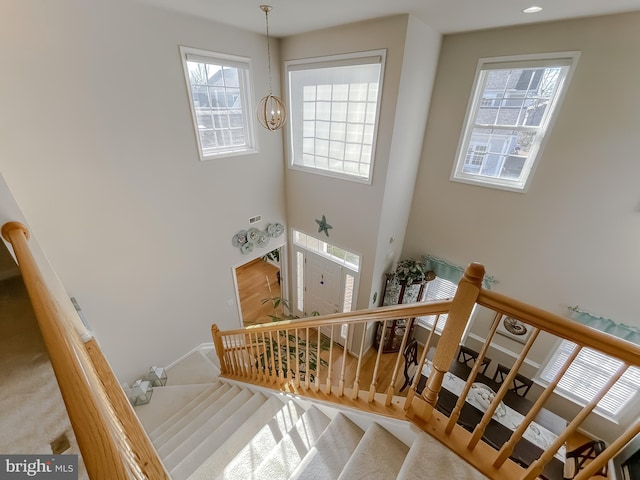 staircase featuring an inviting chandelier and recessed lighting