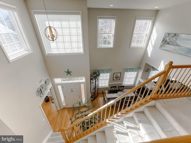 entrance foyer with recessed lighting, a high ceiling, wood finished floors, stairway, and an inviting chandelier