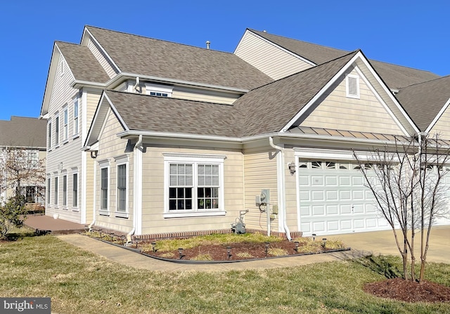 view of front of property featuring an attached garage, a shingled roof, and a front yard