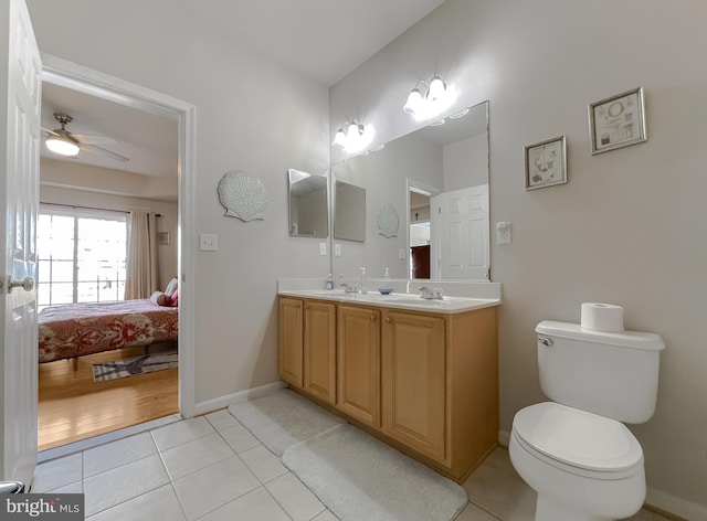 ensuite bathroom with double vanity, toilet, connected bathroom, a sink, and tile patterned flooring