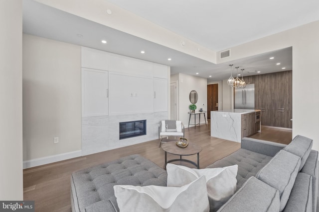 living area with recessed lighting, visible vents, a high end fireplace, wood finished floors, and baseboards