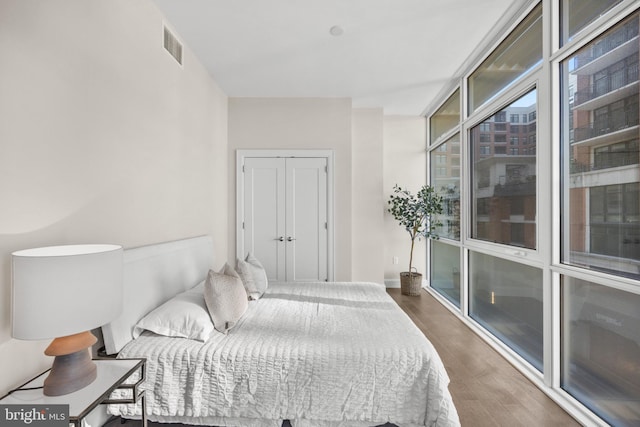 bedroom with expansive windows, visible vents, baseboards, a closet, and dark wood-style floors