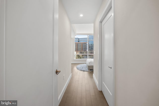 corridor featuring recessed lighting, a view of city, baseboards, and wood finished floors