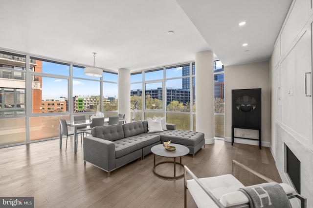 living area featuring a view of city, a wall of windows, wood finished floors, and recessed lighting