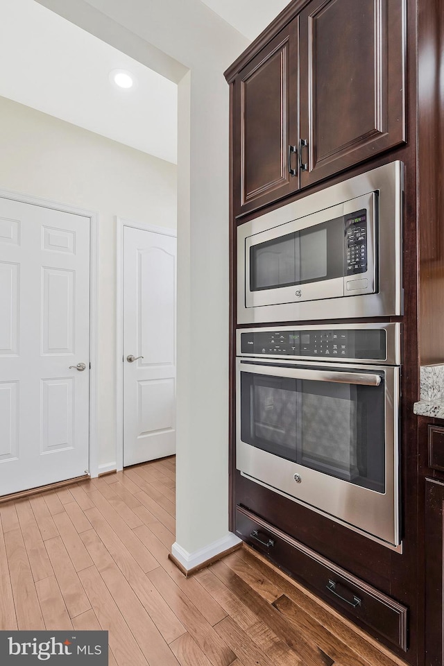 kitchen featuring dark brown cabinetry, baseboards, appliances with stainless steel finishes, light wood-type flooring, and recessed lighting