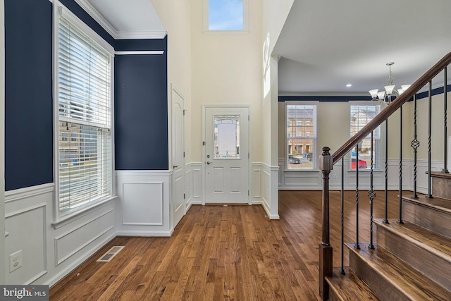 foyer entrance featuring stairs, wood finished floors, a wealth of natural light, and an inviting chandelier