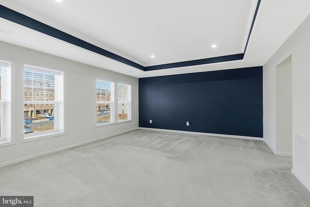 spare room with a tray ceiling, recessed lighting, visible vents, light carpet, and baseboards