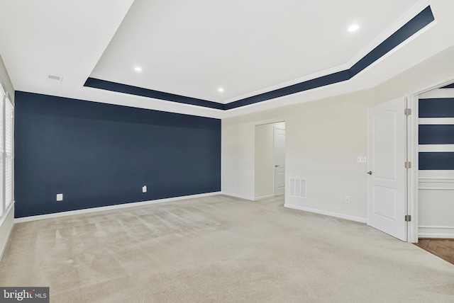 empty room featuring baseboards, a tray ceiling, visible vents, and light colored carpet