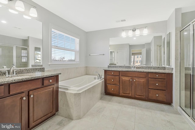 bathroom with a stall shower, two vanities, a sink, and visible vents