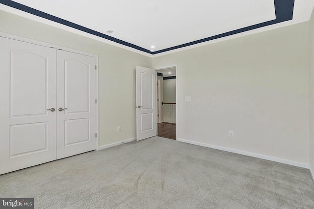 unfurnished bedroom featuring baseboards, a closet, visible vents, and light colored carpet