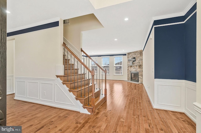 stairway featuring ornamental molding, a fireplace, wood finished floors, and a decorative wall