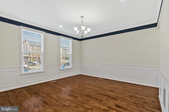 empty room with ornamental molding, dark wood-style flooring, and a notable chandelier