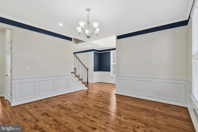 empty room with crown molding, recessed lighting, an inviting chandelier, wood finished floors, and stairs