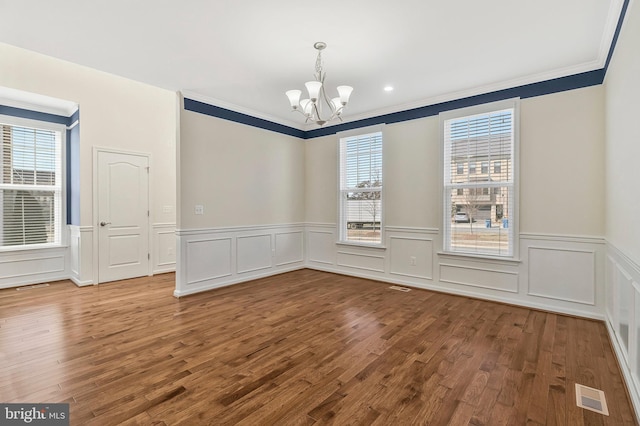 unfurnished dining area with a healthy amount of sunlight, visible vents, a chandelier, and wood finished floors