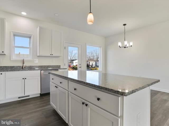 kitchen with visible vents, a center island, dark wood finished floors, stainless steel dishwasher, and a sink