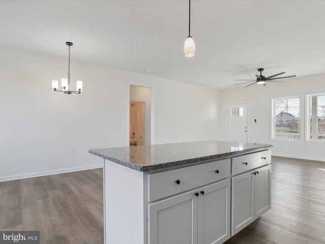 kitchen with dark wood finished floors, dark stone counters, baseboards, and a center island