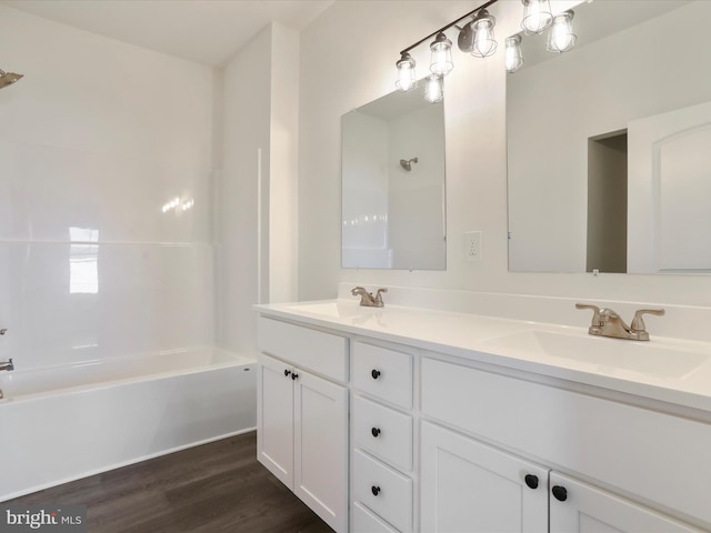 bathroom with double vanity, shower / washtub combination, wood finished floors, and a sink