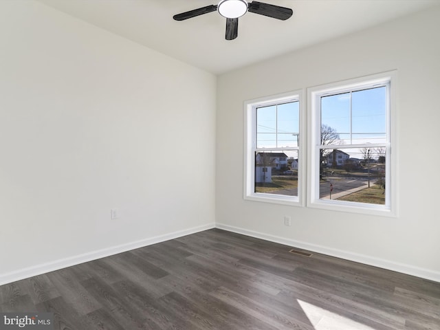 unfurnished room with baseboards, dark wood finished floors, and a ceiling fan